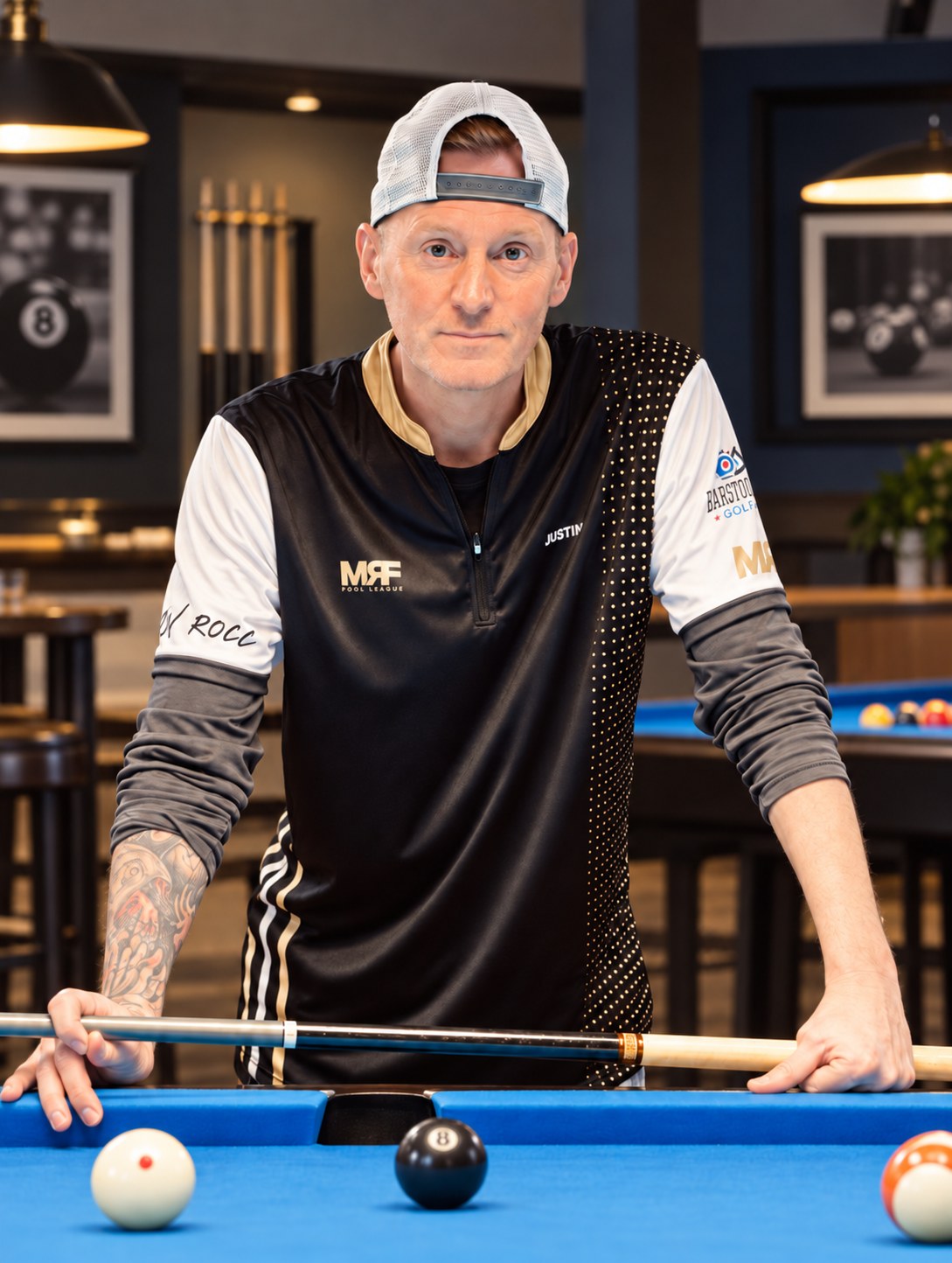 Justin Ingraham standing at a blue-felt billiards table in a pool room